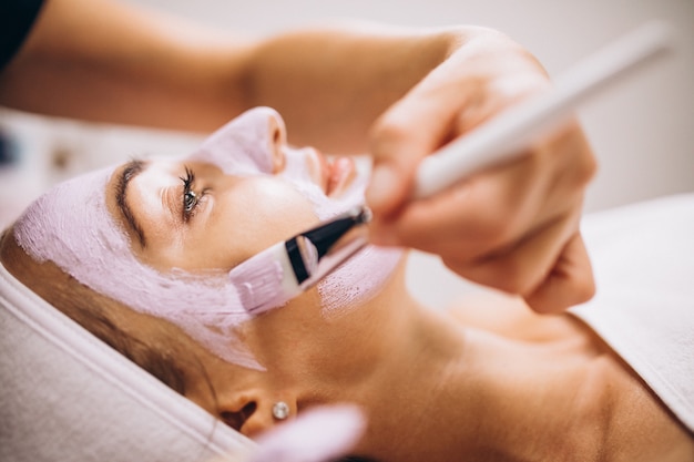 Cosmetologist applying mask on a face of client in a beauty salon