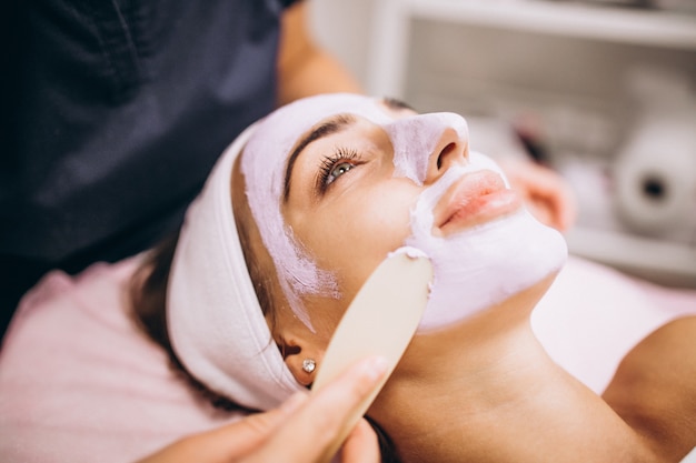 Cosmetologist applying mask on a face of client in a beauty salon