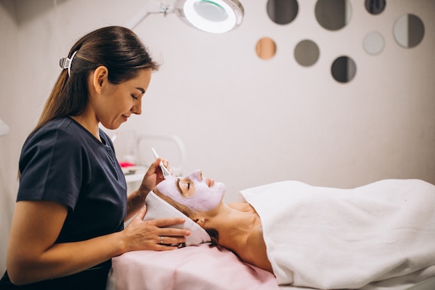 Free Photo cosmetologist applying mask on a face of client in a beauty salon