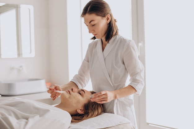 Cosmetologist doing face treatment and applying face mask