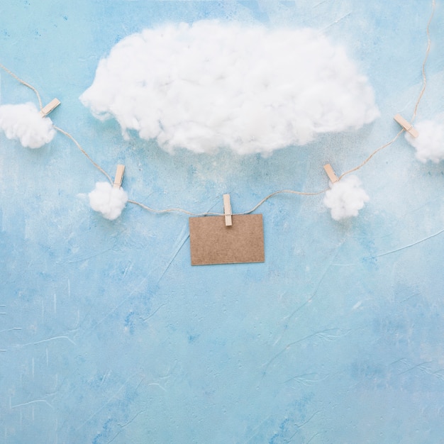 Free Photo cotton clouds over decorative brown card hang with clothespins