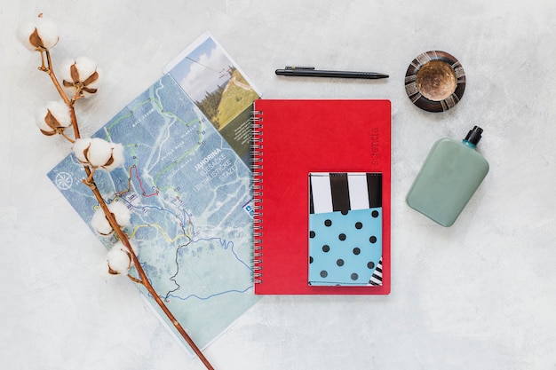 Free photo cotton twig with map, notebook, and wallet on the background