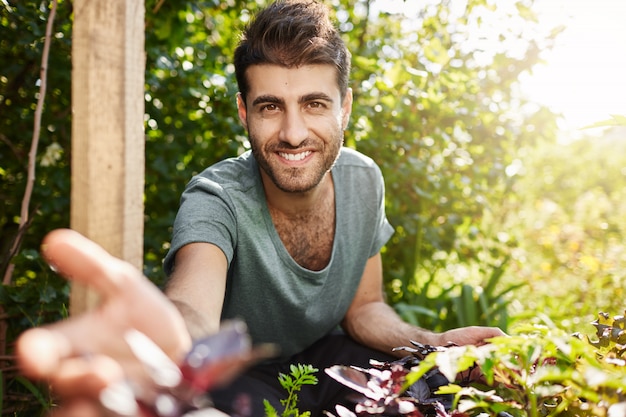 Countryside life, naature. Close up outdoor portrait of young attractive bearded caucasian man in blue t-shirt smiling