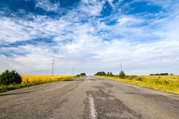 Countryside road among fields Beautiful cloudy sky