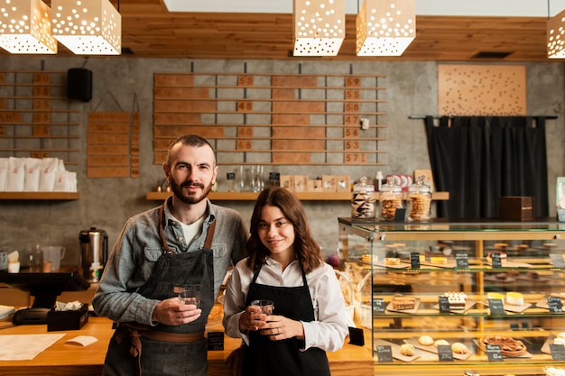 Couple in aprons posing with cups of coffee