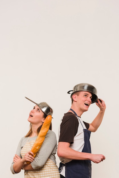 Couple in aprons standing with cookware on heads