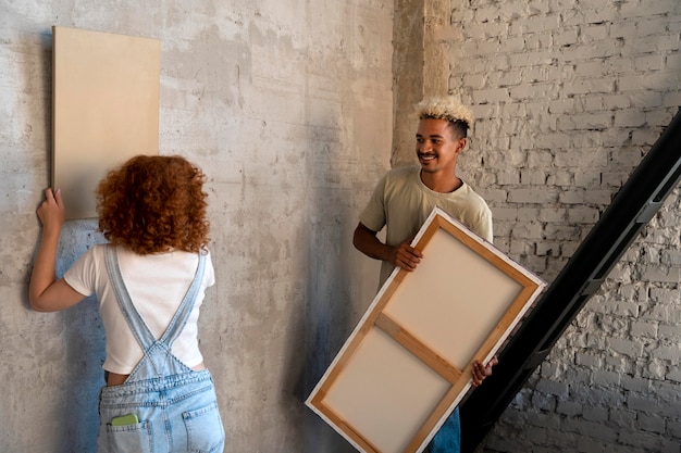 Free Photo couple arranging painting in their new home