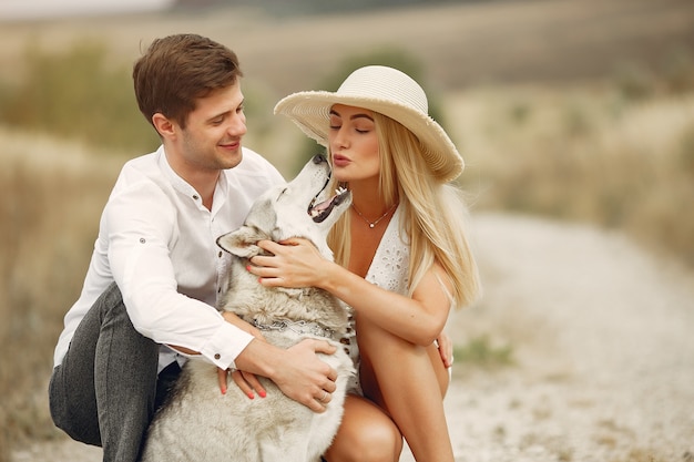 Couple in a autumn field playing with a dog