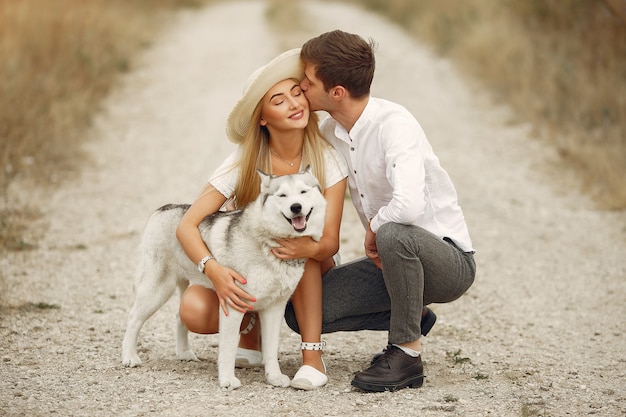 Couple in a autumn field playing with a dog