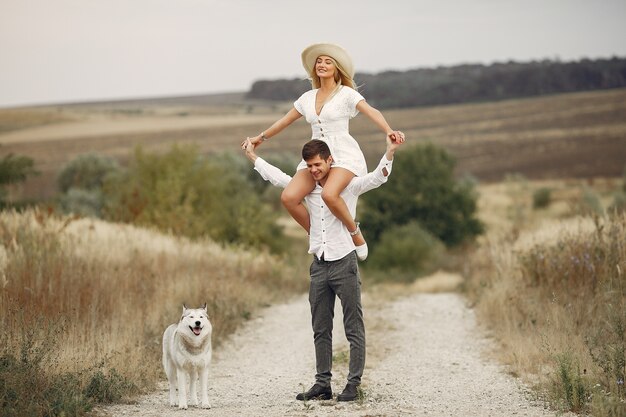 Couple in a autumn field playing with a dog