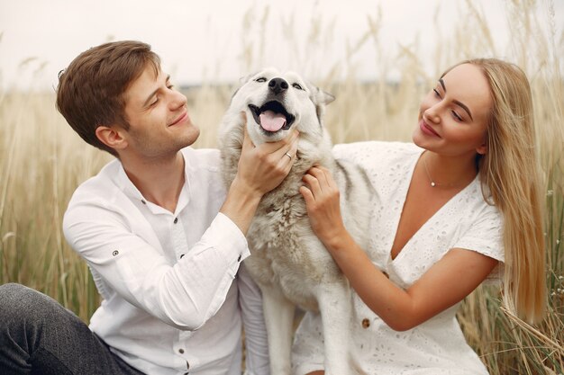 Couple in a autumn field playing with a dog