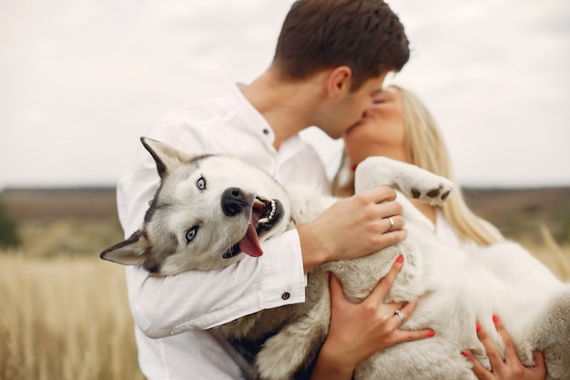 Couple in a autumn field playing with a dog