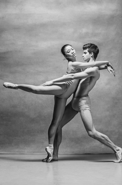 Couple of ballet dancers posing over gray