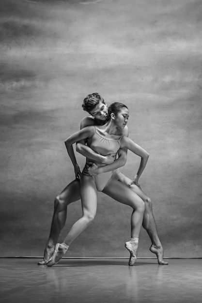 Free photo couple of ballet dancers posing over gray