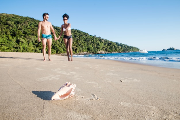 Couple at the beach with seashell in foreground