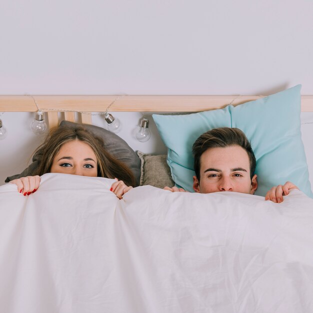 Couple under blanket looking at camera