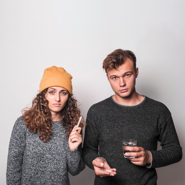 Couple blowing their nose with tissue paper on gray background