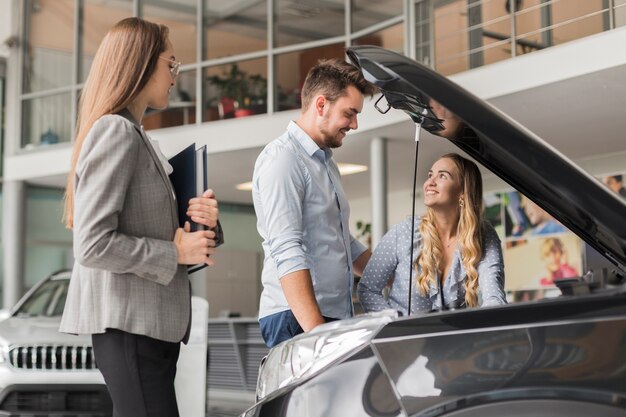 Couple checking car engine in a showroom