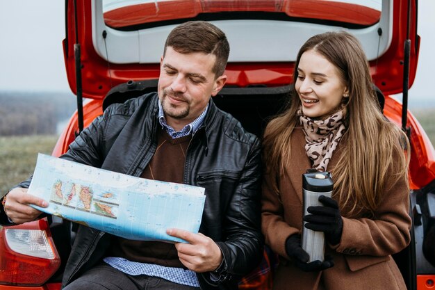 Couple checking a map in the car's trunk