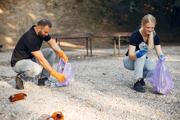 Free photo couple collects garbage in garbage bags in park