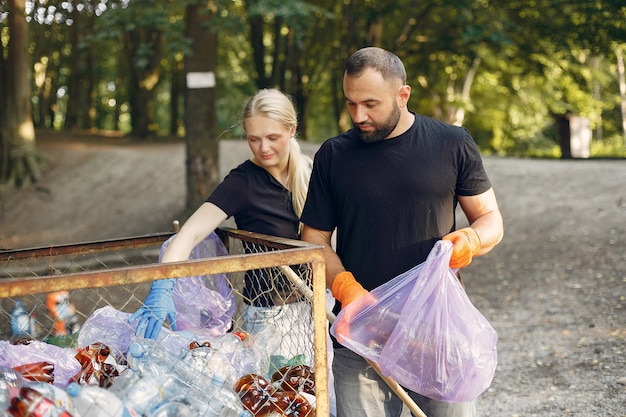 Free photo couple collects garbage in garbage bags in park