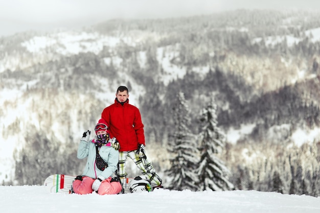 Free photo couple in colorful ski suits poses on the hill somewhere in the mountains