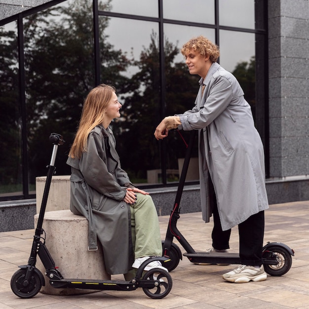 Couple conversing while being outdoors with electric scooters