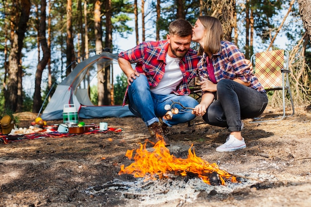 Free Photo couple cooking marshmellow at fire outdoor