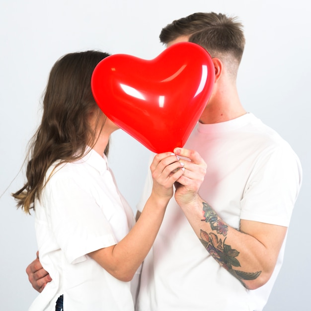 Free photo couple covering faces with heart balloon