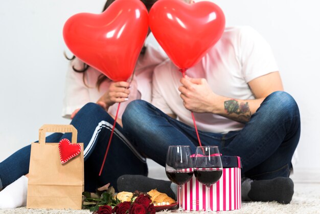 Couple covering faces with red heart balloons 