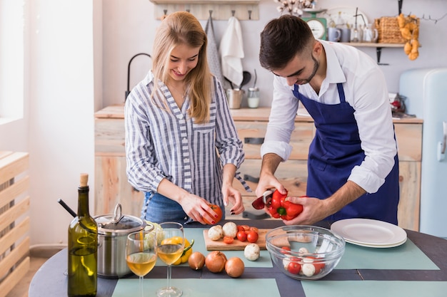 Couple cutting vegetables for salad on board