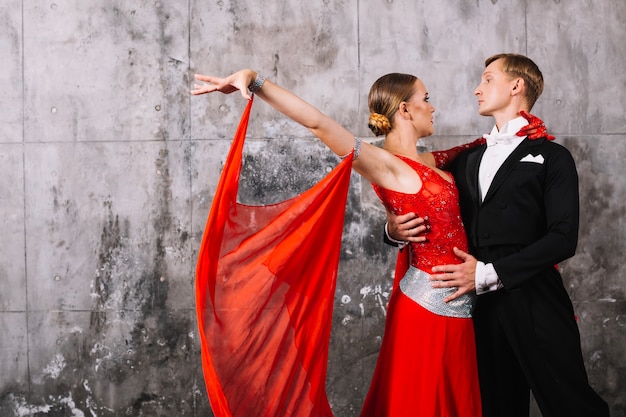 Couple dancing passionate dance near gray wall