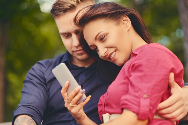 A couple on a date in a city park using smartphone and instant messaging.