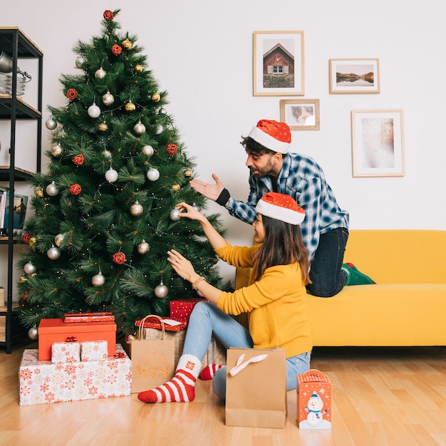 Couple decorating christmas tree at home