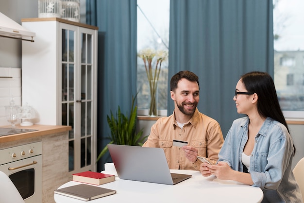 Couple at desk holding smartphone and credit card