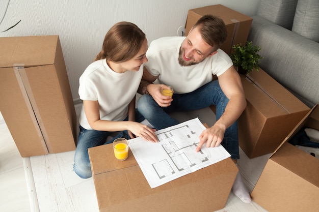 Free photo couple discussing house plan sitting on floor with moving boxes