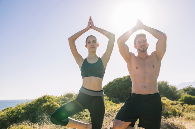 Couple doing yoga exercises in the sun