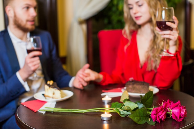 Couple drinking wine and holding hands at table 