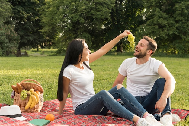 Couple eating grapes con a picnic blanket