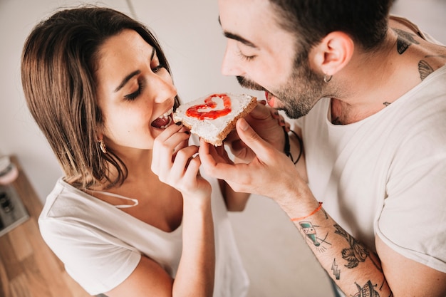 Free photo couple eating toast with jam together