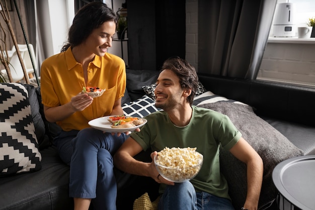 Couple eating together at home on the sofa