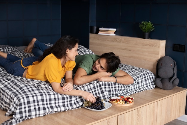 Couple enjoying grapes together at home in bed