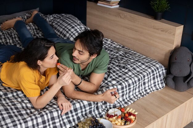 Couple enjoying grapes together at home in bed