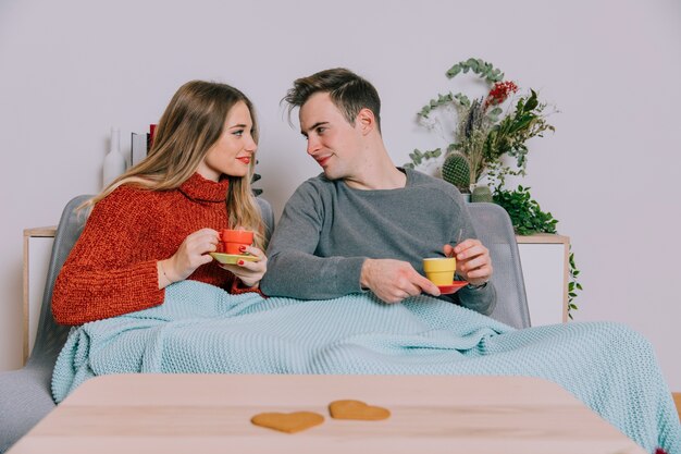 Couple enjoying hot drinks on sofa