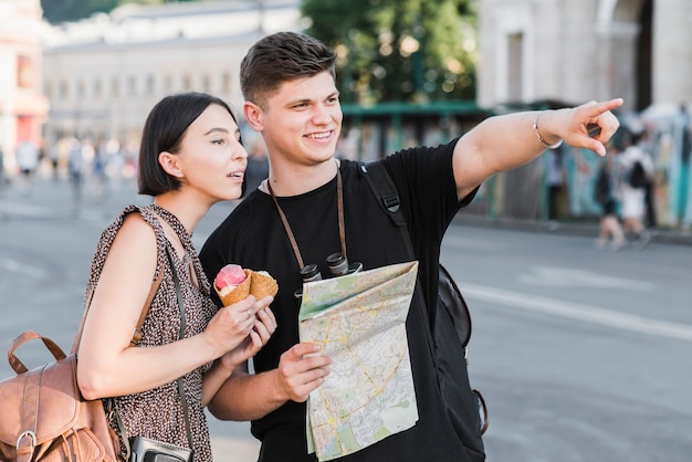 Couple exploring city with map and ice cream