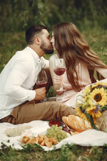 Couple in a field. Brunette in a white dress. Pair sitting on a grass.