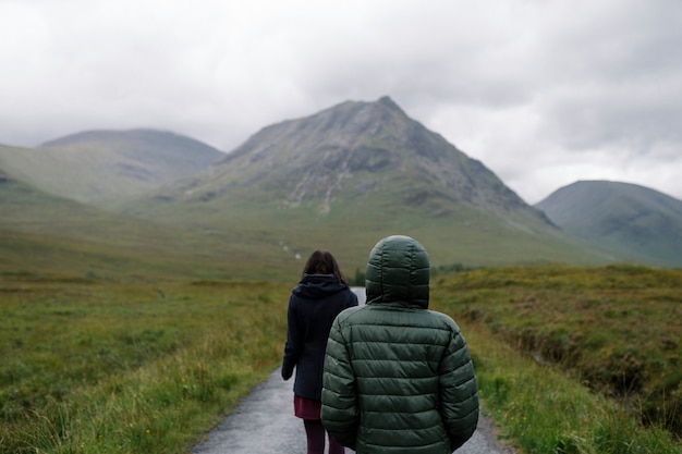 Free photo couple of friends walking through the rain in glen etive, scotland