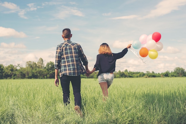 Couple in a greenfield with balloons