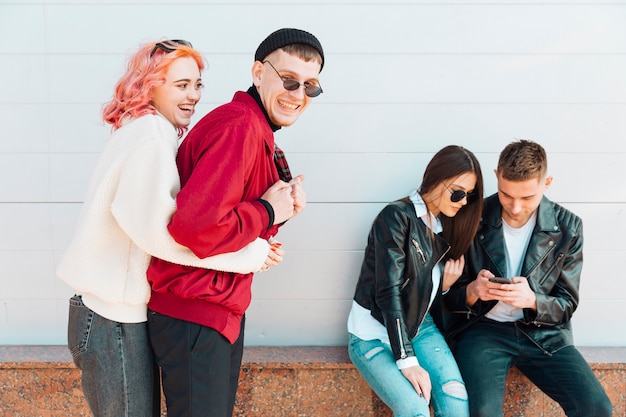 Free photo couple having fun while other pair looking in smartphone