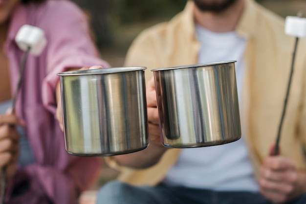 Free photo couple having marshmallows and hot drinks while camping